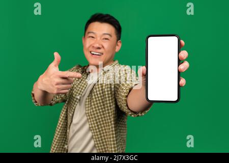 Werbung für mobile Apps. Glücklich asiatische reifen Mann zeigt auf leeren Smartphone-Bildschirm, mockup Stockfoto