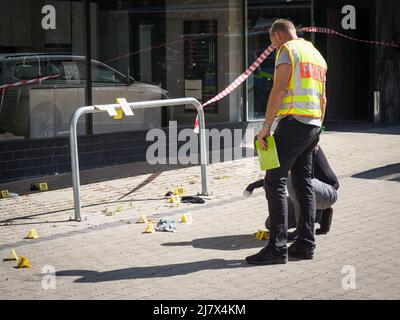 Hanau, Deutschland. 11.. Mai 2022. Forensiker arbeiten auf dem Platz vor einem Hochhaus in der Innenstadt von Hanau, wo heute Morgen ein totes Mädchen gefunden wurde. Vor dem Haus lag ein schwer verletzter Junge auf der Straße. Kredit: Frank Rumpenhorst/dpa/Alamy Live Nachrichten Stockfoto