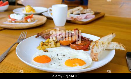 Amerikanisches Frühstück mit Spiegeleiern, Speck, Tomaten, Toast Stockfoto