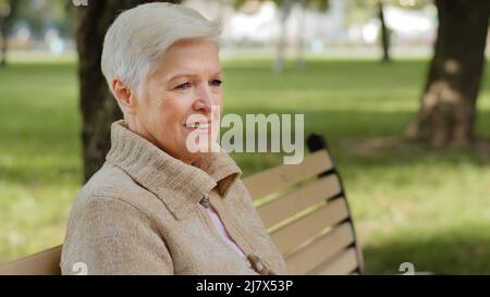 Nahaufnahme faltiges Gesicht von 65s glücklichen älteren Frau im Freien Blick beiseite mit breiten Lächeln, Zahnimplantate und Prothesen zufrieden Kundenporträt Stockfoto
