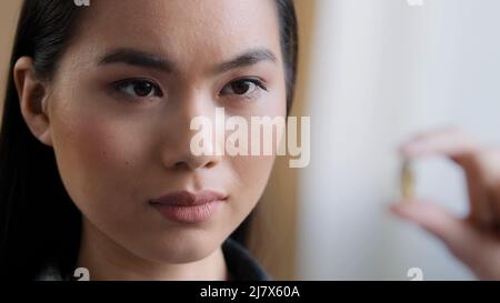 Extreme close-up weiblich verschwommen weibliche Gesicht asiatische Mädchen koreanisch krank kranke Frau hält Vitaminpille hält Medikamentenkapsel gegen Mineralien Nahrung Stockfoto