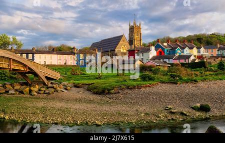 Blick über den Fluss Aeron zur Holy Trinity Church und den unverwechselbaren, farbenfrohen Häusern der Harbour Lane in der wunderschönen Stadt Aberaeron Stockfoto