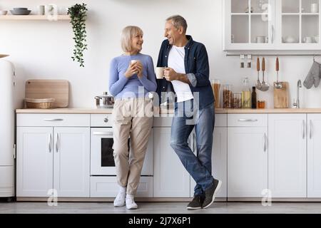 Foto in voller Länge von einem positiven älteren Paar, das Kaffee trinkt Stockfoto