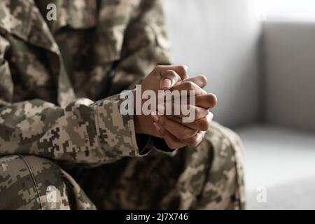 Unverkennbare Schwarze Soldatin, Die Mit Verschlammten Händen Auf Der Couch Sitzt Stockfoto