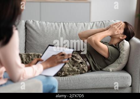 Depressive Soldatin, Die Während Der Therapiesitzung Mit Einem Psychiater Das Gesicht Mit Den Händen Bedeckt Stockfoto