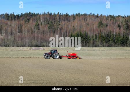 Ländliche Landschaft mit landwirtschaftlichem Traktor und Sämaschine im Feld an einem sonnigen Frühlingstag. Viel Platz für Kopien. Salo, Finnland. 15.Mai 2021. Stockfoto