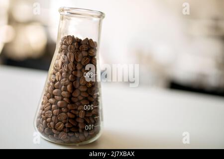 Dunkel geröstete Kaffeebohnen auf dem Tisch im Glas Stockfoto