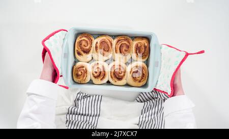 Flach liegend. Glasur frisch gebackene Zimtschnecken in einer blauen Backform. Stockfoto