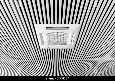 Klimaanlage, die in den Decken im Bürobereich montiert ist. Moderne Decken sind aus weißen und schwarzen Streifen gestaltet. Stockfoto