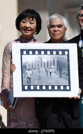 Der mit dem Pulitzer-Preis ausgezeichnete Fotograf Nick Ut (R), flankiert von Kim Phuc, bekannt als das ‘Napalm Girl’, zeigt sein ikonisches Foto aus dem Vietnamkrieg von 1972, als sie am 11. Mai 2022 am Ende der wöchentlichen Generalaudienz auf dem Petersplatz im Vatikan auf Papst Franziskus warten. Stockfoto