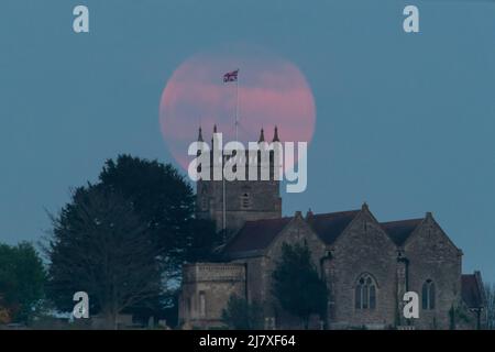 Oldbury-on-Severn, Gloucestershire, Großbritannien. 16.. April 2022. Der vierte Vollmond des Jahres, der Pink Moon, erhebt sich über der St. Arilda's Church in Oldbury-o Stockfoto