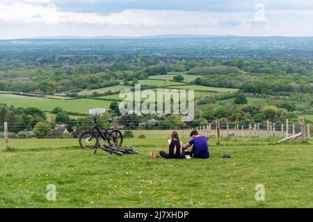 Ein junges Radlerpaar, das sich im South Downs National Park in der Nähe der Windmühlen von Clayton ausruhen und die Landschaft genießen kann, West Sussex, England, Großbritannien Stockfoto