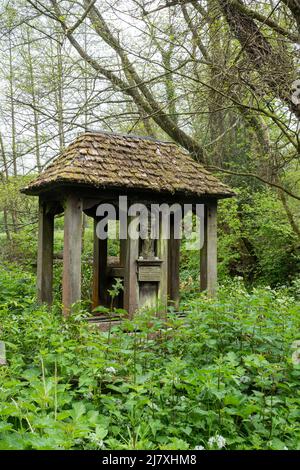 Der Heilige Brunnen in Dunsfold, einem Dorf in Surrey, England, Großbritannien, unter einem Schutz oder Schrein aus alter Eiche mit Schindlerdach und geschnitzter Figur von Maria und Kind Stockfoto