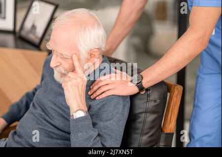 Erfahrener Krankenpfleger, der eine ältere Person tröstet Stockfoto