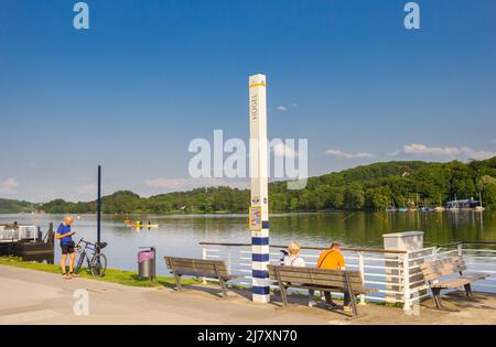 Menschen, die sich auf einer Bank am Bladeney-See in Bredeney, Essen, entspannen Stockfoto