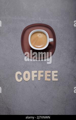 Espresso Kaffee Textwort mit Kaffee serviert auf einer weißen Tasse auf einem strukturierten dunkelgrauen Hintergrund Stockfoto