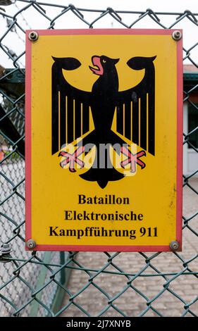 Bramstedtlund, Deutschland. 11.. Mai 2022. An einem Zaun am Eingang zur Aufklärungsstelle der Bundeswehr in Bramstedtlund hängt ein Schild mit der Aufschrift „Battalion Electronic Warfare 911“. Verteidigungsminister Lambrecht besuchte diese Einrichtung am 13. April 2022, in der nach Emissionen im elektromagnetischen Spektrum gesucht, erkannt und bewertet wird. Quelle: Markus Scholz/dpa/Alamy Live News Stockfoto