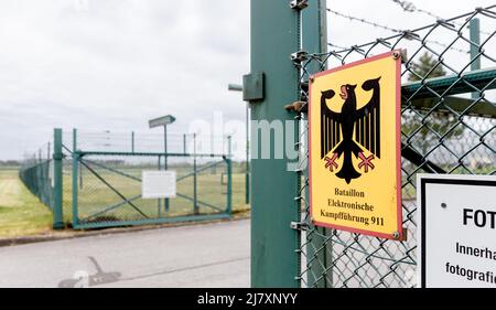 Bramstedtlund, Deutschland. 11.. Mai 2022. An einem Zaun am Eingang zur Aufklärungsstelle der Bundeswehr in Bramstedtlund hängt ein Schild mit der Aufschrift „Battalion Electronic Warfare 911“. Verteidigungsminister Lambrecht besuchte diese Einrichtung am 13. April 2022, in der nach Emissionen im elektromagnetischen Spektrum gesucht, erkannt und bewertet wird. Quelle: Markus Scholz/dpa/Alamy Live News Stockfoto