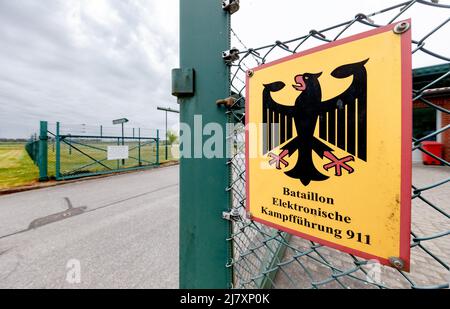 Bramstedtlund, Deutschland. 11.. Mai 2022. An einem Zaun am Eingang zur Aufklärungsstelle der Bundeswehr in Bramstedtlund hängt ein Schild mit der Aufschrift „Battalion Electronic Warfare 911“. Verteidigungsminister Lambrecht besuchte diese Einrichtung am 13. April 2022, in der nach Emissionen im elektromagnetischen Spektrum gesucht, erkannt und bewertet wird. Quelle: Markus Scholz/dpa/Alamy Live News Stockfoto