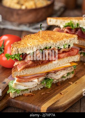 Club Sandwich mit Speck, Schinken, truthahn, Käse, Salat und Tomaten auf geröstetem Brot Stockfoto