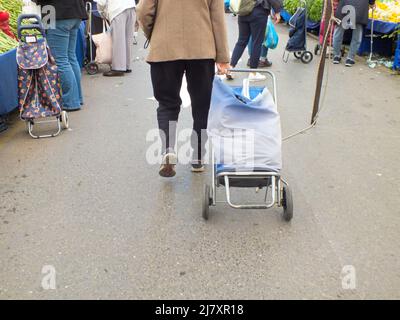 Rückansicht einer älteren Frau, die mit einem Einkaufstasche auf dem lokalen Basar in Istanbul, Türkei, läuft. Leute, die auf dem Bauernmarkt einkaufen Stockfoto