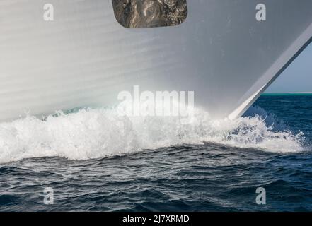 Nahaufnahme des Bogens auf einer großen privaten Luxusmotoryacht, die im tropischen Meer mit Bugwelle unterwegs ist Stockfoto