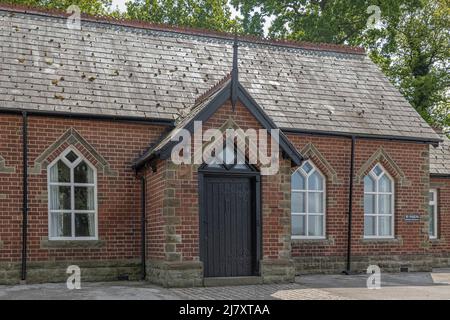 Altes Gebäude mit verzierten schwarzen Holztüren aus roten Ziegeln und Sandsteinblöcken, die als Dorfhaus genutzt wurden Stockfoto