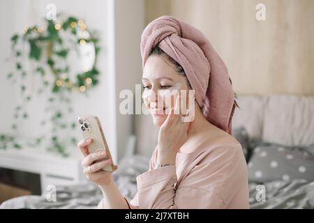 Schöne junge Frau mit Augenflecken, die morgens zu Hause telefonieren Stockfoto