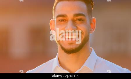 Portrait arabischer Hispanic Mann Geschäftsmann ethnischer bärtiger Kerl trägt formelles Hemd steht im Freien posiert in der Straße in Sonne Sonnenuntergang Blick auf die Kamera Stockfoto