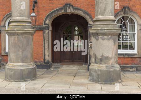 Der große Eingang mit einer prächtigen Säule, die in ein herrschaftliches Haus mit hölzernen Doppeltüren und Fenstern durch einen Bogen eintritt Stockfoto