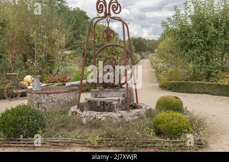 Handpumpe im Garten eines Schlosses aus rostigem Metall und einem Kreis aus altem Stein Stockfoto