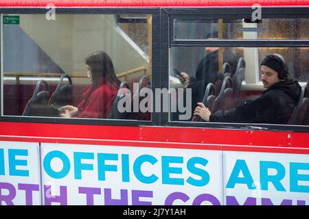 Passagiere, einige tragen eine Maske, andere nicht, werden in einem Doppeldeckerbus in der City of London gesehen. Stockfoto