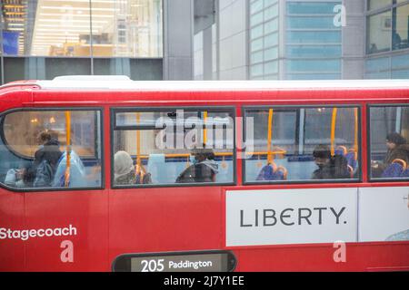 Passagiere, einige tragen eine Maske, andere nicht, werden in einem Doppeldeckerbus in der City of London gesehen. Stockfoto