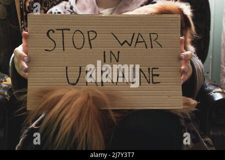 Stoppen Sie den Krieg in der Ukraine geschrieben auf einem Zeichen, dass eine Frau in ihren Händen hält von ihrem Haus in der Dnjepr, Protestaktion, Kriegsrecht in der Ukraine Stockfoto