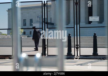 Ein Polizeibeamter geht hinter den Schutzzaun, während Menschen um die Polizeibarrikaden und den Zaun, der den Obersten Gerichtshof der Vereinigten Staaten in Washington, DC, umgibt, am Mittwoch, den 11. Mai 2022, navigieren. Der Senat soll heute eine Verfahrensabstimmung über das Frauengesundheitsschutzgesetz von 2022 anberaumt haben. Kredit: Rod Lamkey/CNP /MediaPunch Stockfoto