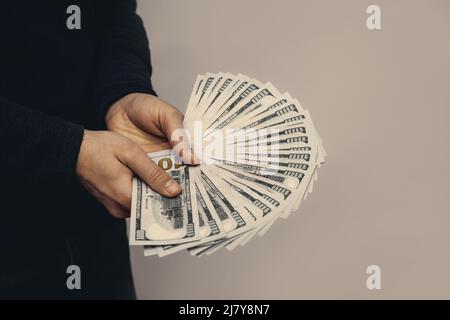 Ein Mann hält einen Fan von 100-Dollar-Scheinen in den Händen. Stockfoto