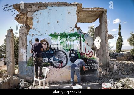 11. Mai 2022, Syrien, Binnish: Syrische Künstler malen in Solidarität mit dem ermordeten palästinensischen Reporter von Al Jazeera, Shireen Abu Aklei, ein Wandgemälde an einer Wand eines zerstörten Hauses in Idlib. Abu Aklei, 51, eine prominente Persönlichkeit im arabischen Nachrichtendienst des Al-Jazeera-Kanals, wurde heute während einer Konfrontation zwischen israelischen Soldaten und Palästinensern in der Stadt Jenin im Westjordanland getötet. Der katarische TV-Sender Al-Jazeera beschuldigt das israelische Militär des "Mordes", aber das israelische Militär sagt, Abu Aklei sei von palästinensischen Schützen geschossen worden, als sie mit seinen Truppen zusammenschlugen. Foto: Anas Alkhar Stockfoto