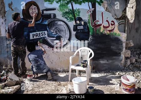 11. Mai 2022, Syrien, Binnish: Syrische Künstler malen in Solidarität mit dem ermordeten palästinensischen Reporter von Al Jazeera, Shireen Abu Aklei, ein Wandgemälde an einer Wand eines zerstörten Hauses in Idlib. Abu Aklei, 51, eine prominente Persönlichkeit im arabischen Nachrichtendienst des Al-Jazeera-Kanals, wurde heute während einer Konfrontation zwischen israelischen Soldaten und Palästinensern in der Stadt Jenin im Westjordanland getötet. Der katarische TV-Sender Al-Jazeera beschuldigt das israelische Militär des "Mordes", aber das israelische Militär sagt, Abu Aklei sei von palästinensischen Schützen geschossen worden, als sie mit seinen Truppen zusammenschlugen. Foto: Anas Alkhar Stockfoto