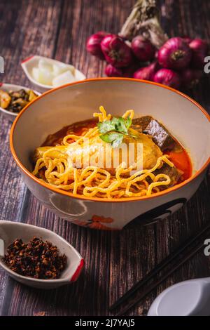 Khao Soi Kai, köstliche Gerichte aus dem Norden Thailands, mit Gewürzen auf dem Tisch arrangiert. Stockfoto