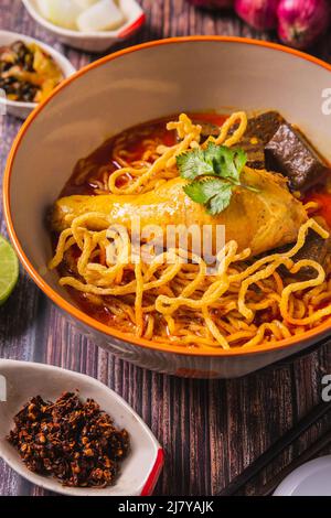 Khao Soi Kai, köstliche Gerichte aus dem Norden Thailands, mit Gewürzen auf dem Tisch arrangiert. Stockfoto
