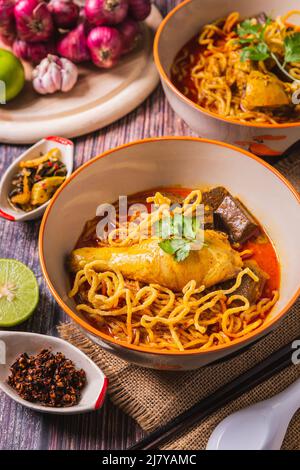 Khao Soi Kai, köstliche Gerichte aus dem Norden Thailands, mit Gewürzen auf dem Tisch arrangiert. Stockfoto