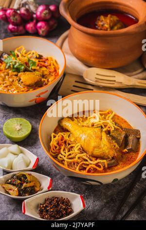 Khao Soi Kai, köstliche Gerichte aus dem Norden Thailands, mit Gewürzen auf dem Tisch arrangiert. Stockfoto