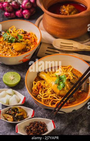 Khao Soi Kai, köstliche Gerichte aus dem Norden Thailands, mit Gewürzen auf dem Tisch arrangiert. Stockfoto