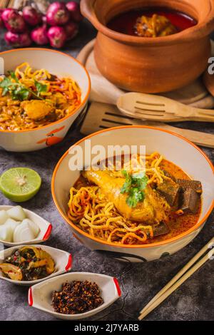 Khao Soi Kai, köstliche Gerichte aus dem Norden Thailands, mit Gewürzen auf dem Tisch arrangiert. Stockfoto