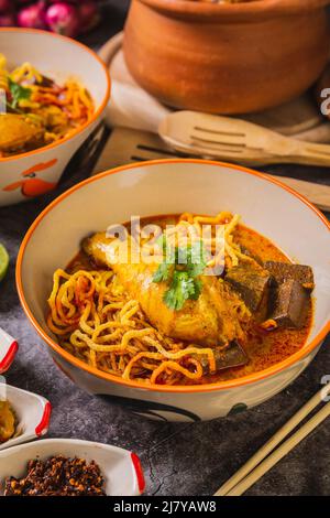 Khao Soi Kai, köstliche Gerichte aus dem Norden Thailands, mit Gewürzen auf dem Tisch arrangiert. Stockfoto
