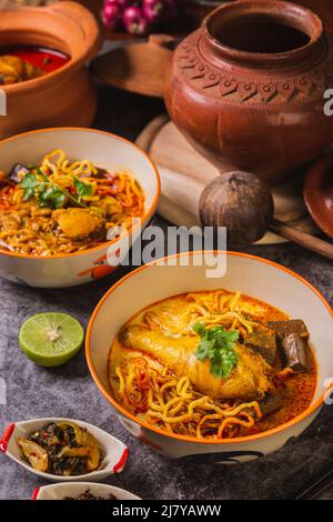 Khao Soi Kai, köstliche Gerichte aus dem Norden Thailands, mit Gewürzen auf dem Tisch arrangiert. Stockfoto