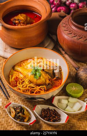 Khao Soi Kai, köstliche Gerichte aus dem Norden Thailands, mit Gewürzen auf dem Tisch arrangiert. Stockfoto