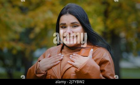 Porträt erstaunt hispanischen glückliches Mädchen erhält unerwartete Überraschung im Park im Freien junge enthusiastische Frau freut sich, die Hände auf Brust weiblich Stockfoto