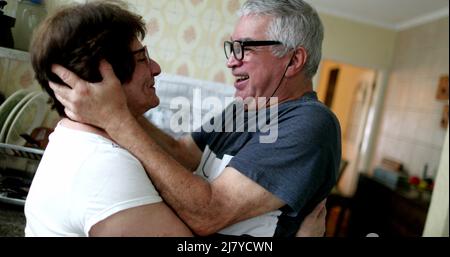 Glücklicher Ehemann umarmte Frau, nachdem er positive Nachrichten auf dem Smartphone erhalten hatte Stockfoto
