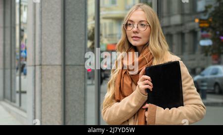Erfolgreiche junge Geschäftsfrau stehen im Freien in der Stadt nachdenkliche kaukasische Dame halten schwarzen Ordner mit Dokumenten Vertrag schönen Studenten Mädchen mit Stockfoto